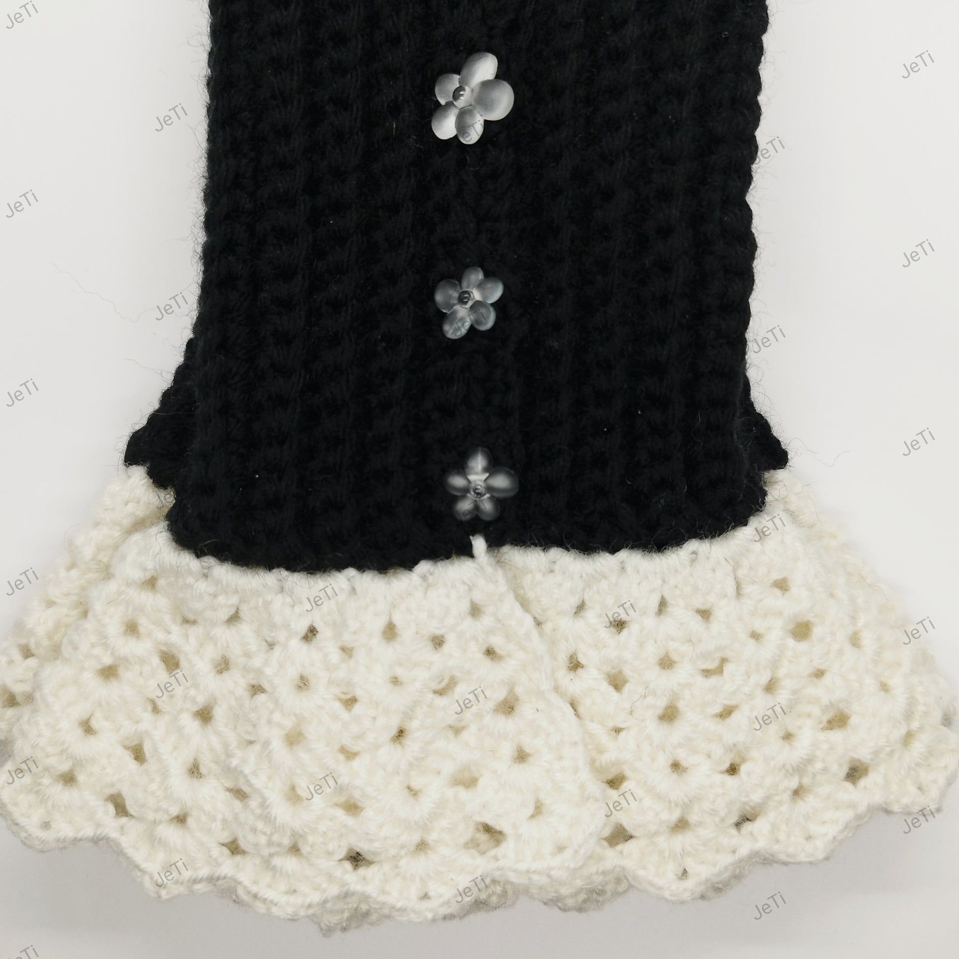 Close-up of handmade black crochet wrist cuffs with decorative flower buttons and lace trim