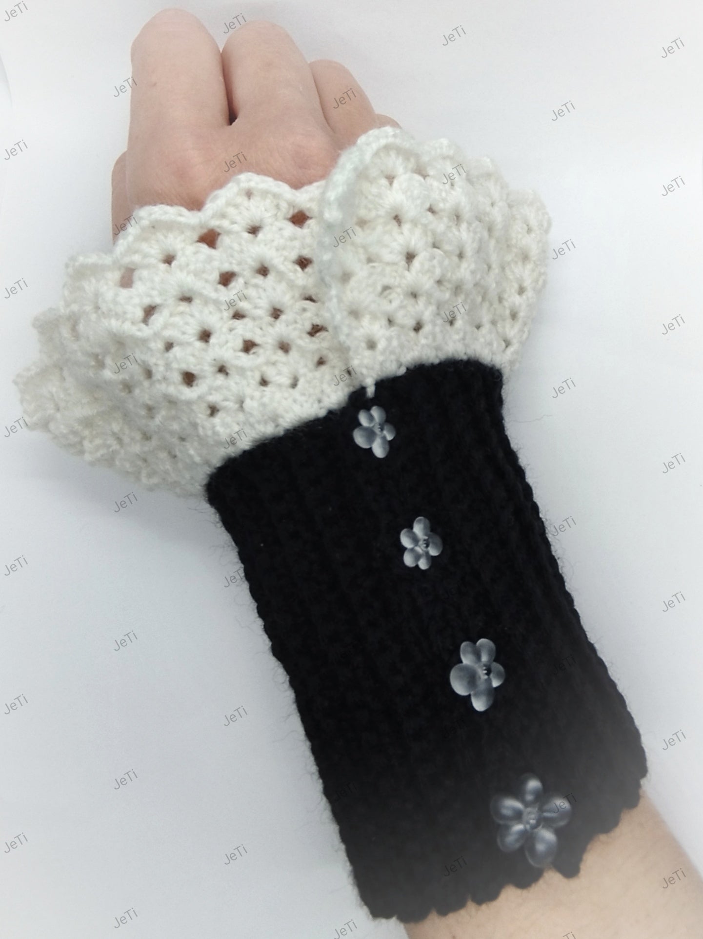 Pair of handmade black and white crochet wrist cuffs laid flat with lace edges and floral details