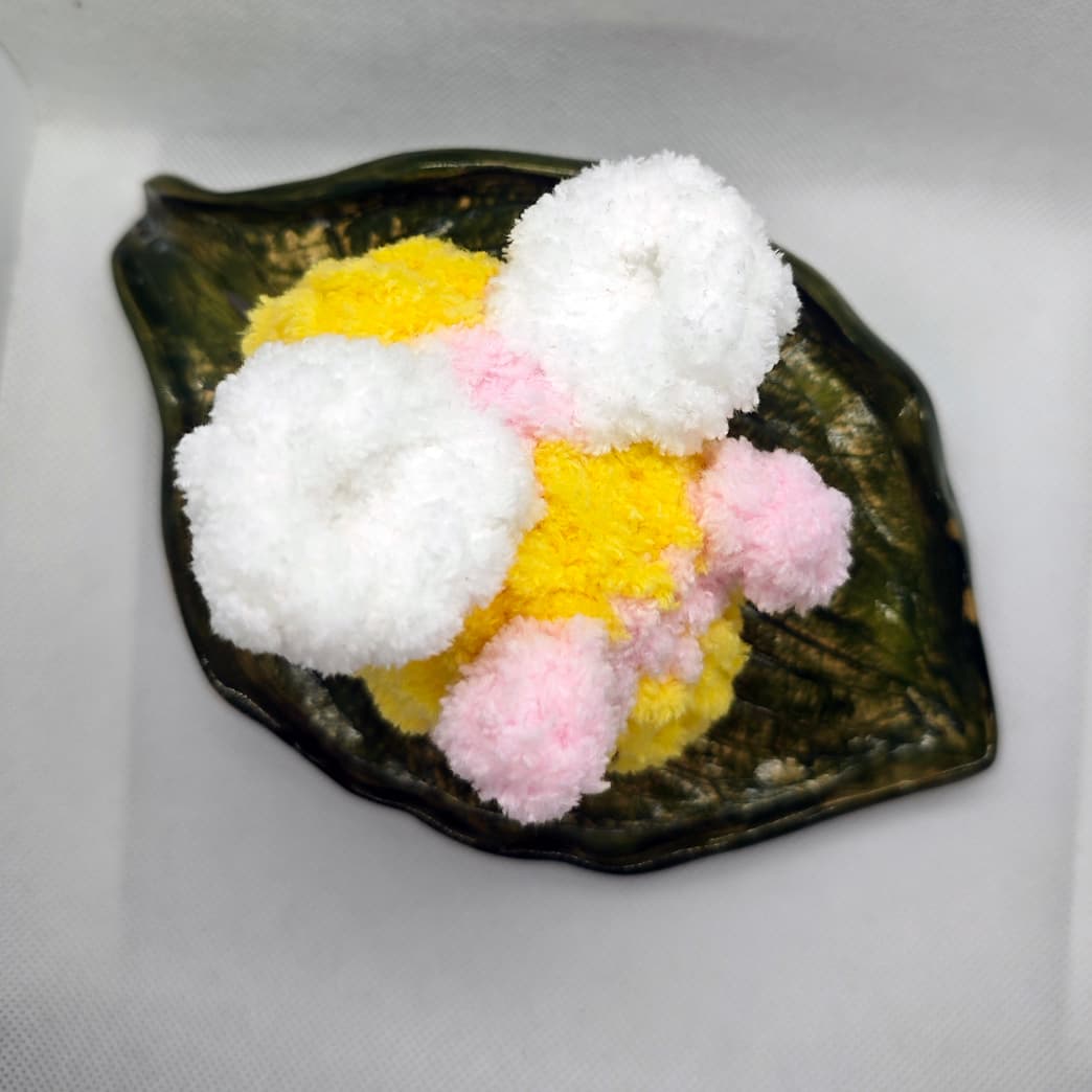 Top view of handmade pink and yellow amigurumi bee plush with soft white wings