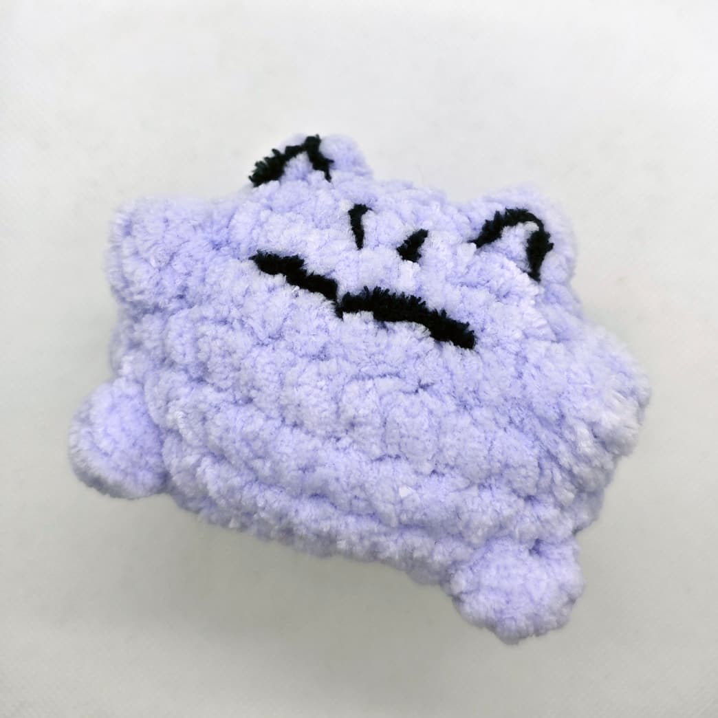 Side view of handmade purple amigurumi frog plush toy with soft texture