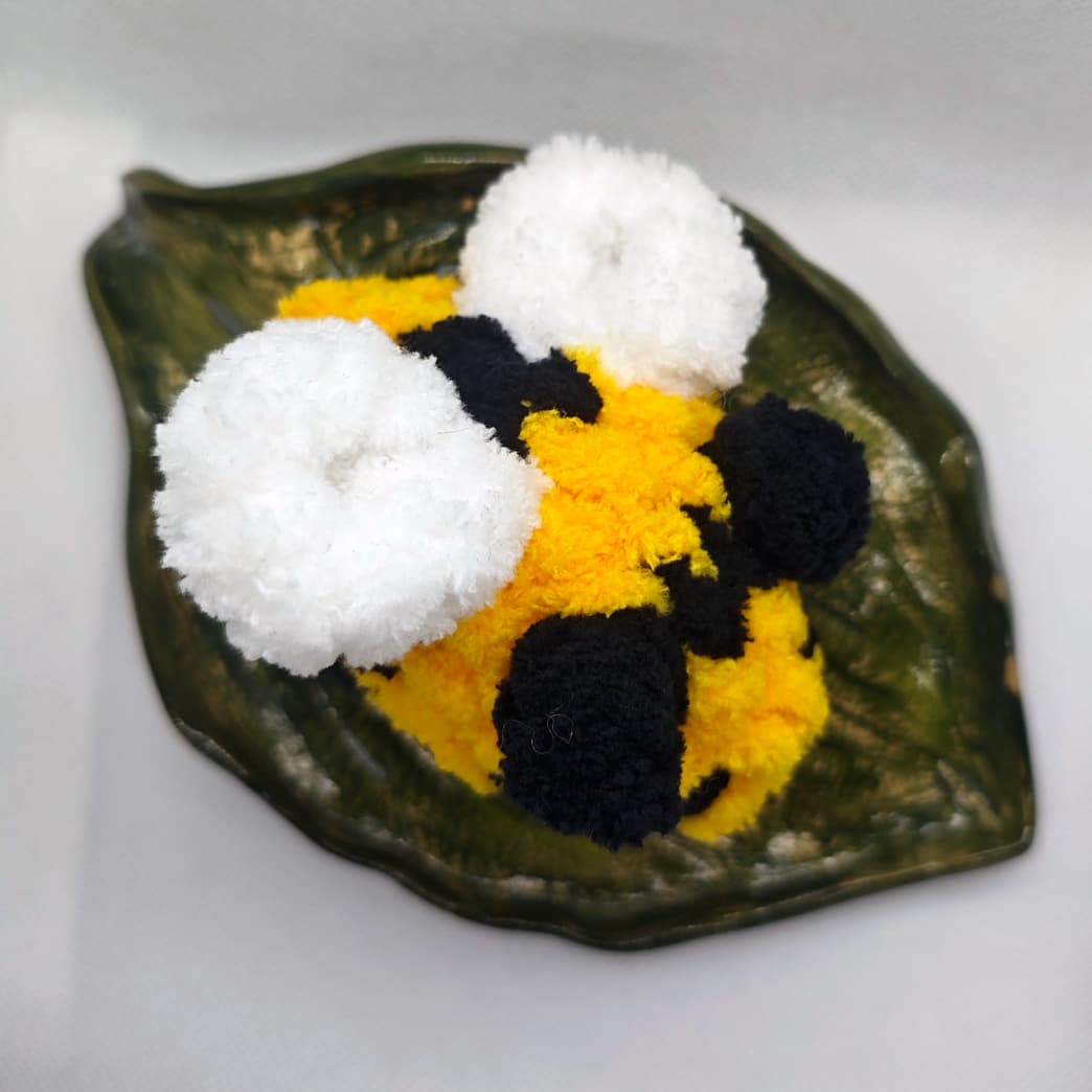 Top view of handmade yellow and black crochet bee plush toy with white wings